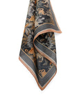 Charcoal silk cotton scarf with gold, bronze, and cream botanical and animal motifs, rolled display. Illustrated by Lisel Ashlock.