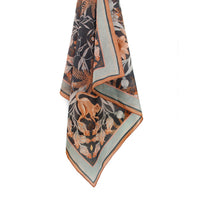 Silk cotton scarf in moonstone with botanical and animal motifs featuring monkeys, ferns, and flowers in black, orange, and cream. Illustrated by Lisel Ashlock.