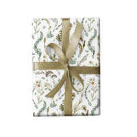 Gift wrap with botanical illustrations of wildflowers and herbs tied with a tan ribbon bow. Illustrated by Lisel Ashlock.