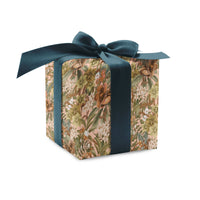 A square gift box wrapped in floral hellebore rose patterned paper with a teal silk ribbon bow on top. Illustrated by Lisel Ashlock.