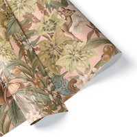 Rolled gift wrap featuring a botanical pattern with pink hellebore flowers, green leaves, berries, and woodland deer on a blush background. Illustrated by Lisel Ashlock.