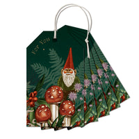 A fan of green gift tags featuring a gnome with a red hat surrounded by red mushrooms and wildflowers, illustrated by Lisel Ashlock.