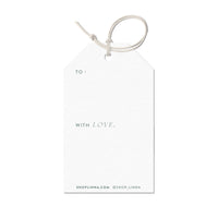 A cream gift tag with "TO:" at top and "WITH LOVE," in the middle, attached with twine. Illustrated by Lisel Ashlock.