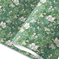 Green gift wrap with white magnolia flowers, green leaves, and small birds among botanical foliage. Illustrated by Lisel Ashlock.