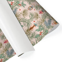 Rolled gift wrap featuring festive botanical illustration with evergreen branches, red berries, and ornamental birds on cream background. Illustrated by Lisel Ashlock.