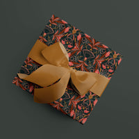 Wrapped gift with ornate floral patterned paper in red, orange, and gold tones with a golden ribbon bow. Illustrated by Lisel Ashlock.