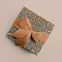 Apricot gift wrap with ornate floral pattern tied with tan ribbon bow on beige background. Illustrated by Lisel Ashlock.