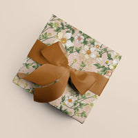 A wrapped gift with pink floral anemone patterned paper and a bronze grosgrain ribbon bow, viewed from above. Illustrated by Lisel Ashlock.