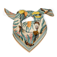 Banksia Sun silk cotton scarf with teal leaves, yellow flowers, brown birds, and striped border. Illustrated by Lisel Ashlock.