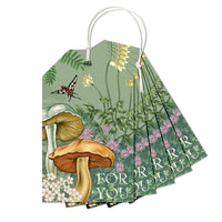 A fan of illustrated gift tags featuring woodland flowers, mushrooms, and insects with "For You" text, illustrated by Lisel Ashlock.