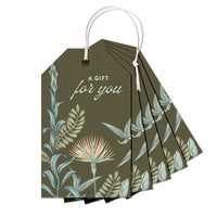 A fan of olive green gift tags with botanical lily illustrations and white string, displaying "A gift for you" text. Illustrated by Lisel Ashlock.
