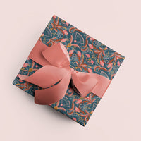 Blue Rose patterned gift wrap with coral ribbon bow on beige background. Illustrated by Lisel Ashlock.
