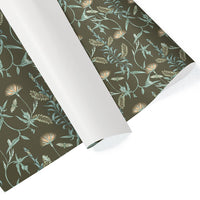 Rolled gift wrap featuring botanical illustration of lilies, ferns, and insects on dark green background. Illustrated by Lisel Ashlock.
