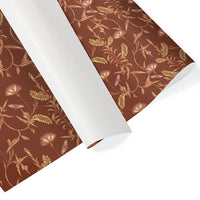Rolled gift wrap with botanical lily tree pattern in rust and gold tones on brown background. Illustrated by Lisel Ashlock.