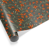 A roll of orange floral gift wrap on a gray background featuring scattered blooms and green stems illustrated by Lisel Ashlock.