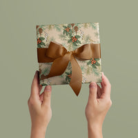Two hands holding wrapped gift with Holly & Hare in Blush pattern and brown ribbon bow against sage background. Illustrated by Lisel Ashlock.