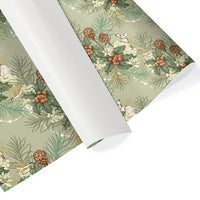 Rolls of gift wrap featuring a woodland pattern with holly, berries, pinecones, and hares on a mint green background. Illustrated by Lisel Ashlock.
