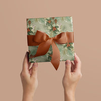 Hands holding wrapped gift with Holly & Hare mint green wrapping paper and rust ribbon bow. Illustrated by Lisel Ashlock.