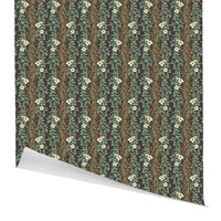 Rolled gift wrap featuring a repeating pattern of gold fern fronds, green eucalyptus leaves, white flowers, and red berries on a dark background. Illustrated by Lisel Ashlock.