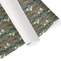 Rolls of gift wrap featuring botanical pattern with green foliage, white flowers, and red berries on dark background. Illustrated by Lisel Ashlock.