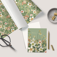 Flat lay of a floral thank you greeting card surrounded by matching wrapping paper, scissors, pen, and desk accessories. Illustrated by Lisel Ashlock.