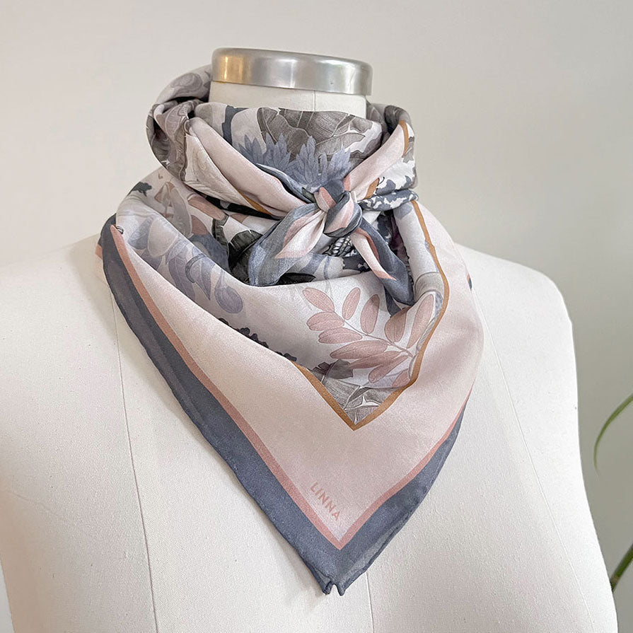 Angelite silk cotton scarf in soft pink and gray tones with botanical leaf design, draped on mannequin. Illustrated by Lisel Ashlock.