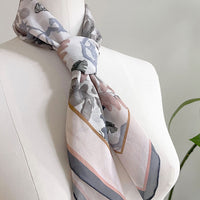 Angelite silk cotton scarf with botanical illustrations in soft gray, blush, and cream tones draped on a dress form. Illustrated by Lisel Ashlock.