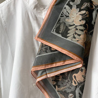 Folded silk cotton scarf in charcoal with botanical illustration in cream and copper tones. Illustrated by Lisel Ashlock.