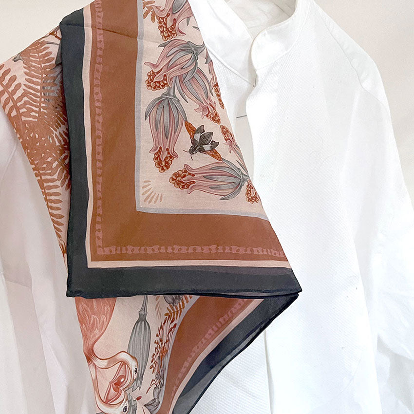 Sunstone silk cotton scarf featuring botanical illustrations of flowers and ferns in terracotta, navy, and cream tones. Illustrated by Lisel Ashlock.