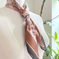 Sunstone silk cotton scarf with botanical leaf patterns in terracotta and gray tones, draped on a mannequin. Illustrated by Lisel Ashlock.