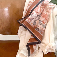 Silk cotton scarf in sunstone featuring botanical illustrations of flowers and ferns in rust and cream tones. Illustrated by Lisel Ashlock.
