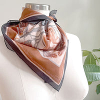 Sunstone silk cotton scarf draped on mannequin with decorative figures and earth tones. Illustrated by Lisel Ashlock.