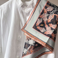 Silk cotton scarf with botanical floral pattern in coral and black tones draped over white shirt. Illustrated by Lisel Ashlock.