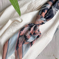 Silk cotton scarf with detailed botanical illustrations in coral, navy, and taupe tones laid on white linen. Illustrated by Lisel Ashlock.