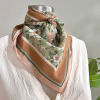 Floral silk cotton scarf in green and blush tones tied around mannequin neck. Illustrated by Lisel Ashlock.