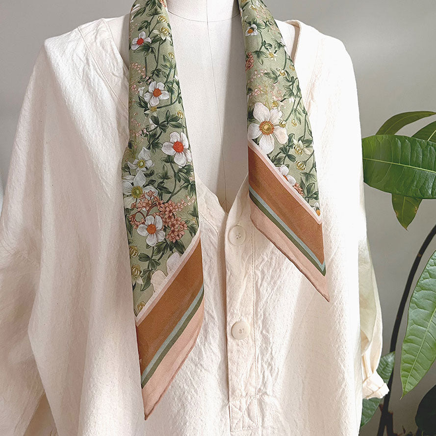 Silk cotton scarf in medium size with anemone Ceylon green floral pattern worn around neck of white linen shirt. Illustrated by Lisel Ashlock.