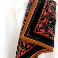 Folded silk cotton scarf in bright mahogany filigree pattern with red, gold, and black floral design. Illustrated by Lisel Ashlock.
