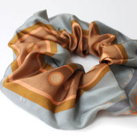 Apricot striped silk scrunchie in warm tones of cream, tan, and dusty blue, gathered in a decorative bunch. Illustrated by Lisel Ashlock.