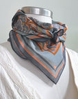 A silk cotton scarf with apricot filigree pattern draped around a mannequin wearing a white shirt. Illustrated by Lisel Ashlock.