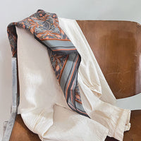 Silk cotton scarf with apricot filigree pattern draped over wooden chair. Illustrated by Lisel Ashlock.