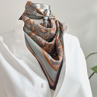 Apricot Filigree silk cotton scarf displayed on a dress form with ornate floral pattern in orange and charcoal. Illustrated by Lisel Ashlock.