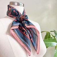 Blue rose filigree silk cotton scarf draped on a dress form mannequin next to a potted plant. Illustrated by Lisel Ashlock.