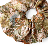 Silk scrunchie with rose hellebore floral pattern in cream, green, orange, and brown tones. Illustrated by Lisel Ashlock.