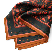 Folded silk twill scarf with mahogany filigree floral pattern on dark background and gold border. Illustrated by Lisel Ashlock.