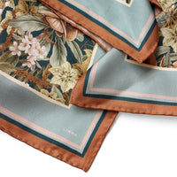 Folded silk twill scarf featuring midnight hellebore florals with brown border and LINNA branding, illustrated by Lisel Ashlock.
