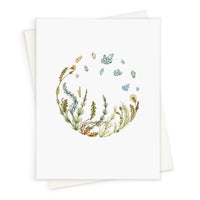 Blank greeting card featuring watercolor illustration of herbs and crystals arranged in a circle, Illustrated by Lisel Ashlock.