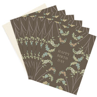 Stack of happy birthday greeting cards with sage green background and hanging floral botanical design illustrated by Lisel Ashlock.