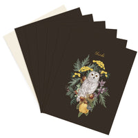 Stack of thank you greeting cards featuring a snowy owl surrounded by yellow flowers and foliage on dark background. Illustrated by Lisel Ashlock.