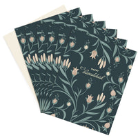 Stack of Happy Hanukkah greeting cards with dark teal background featuring illustrated flowers in peach and sage green. Illustrated by Lisel Ashlock.