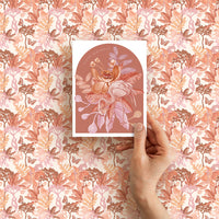 Hand holding a "Happy Birthday" greeting card with illustrated flamingo and flowers on terracotta background. Illustrated by Lisel Ashlock.
